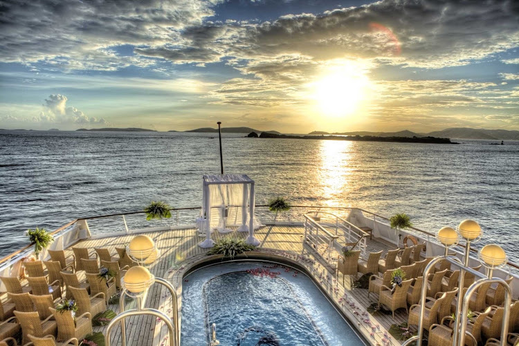 A wedding ceremony is set up on the main deck of a SeaDream yacht at sunset.