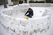 Jeremy Seidt, 44, packs snow that he shoveled off his driveway into an empty cat litter bucket as he works on making an igloo in the front yard of his Sharon Township home in Columbus, Ohio, US February 15, 2021. 