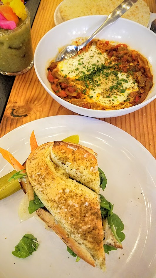 Shalom Y'all options for brunch at Pine Street Market of Shakshuka with tomatoes, peppers, baked eggs; a Jerusalem Bagel Sandwich with house-smoked mackerel, pickles, za’atar, and herbed labneh; and a Shalom Mary with vodka, tomatillo, cucumber, celery, s’hug, and za’atar salt