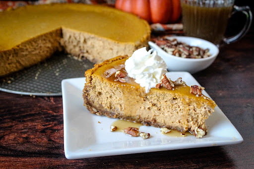 A slice of Pumpkin Cheesecake With Gingersnappy Crust with whipped cream.