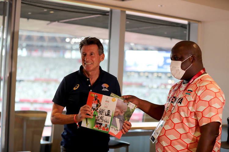 IAAF President Sebastian Coe (L) receives handbook from top Kenyan journalist Elias Makori in Tokyo