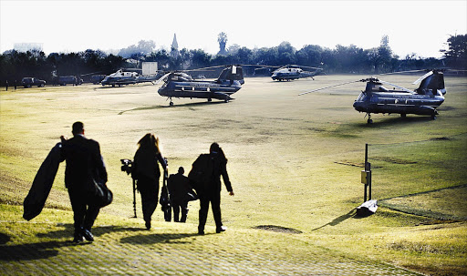 Members of the White House travelling staff walk to a group of helicopters about to transport President Barack Obama from a soccer field in Johannesburg