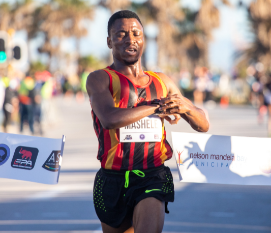 Gauteng's Precious Mashele stops his watch as he breaks the tape to claim his first national half marathon title at the Nelson Mandela Bay Half Marathon.