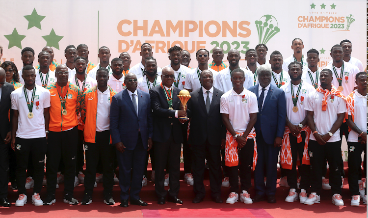 Ivorian Football Federation boss Yacine Idriss Diallo with trophy, poses with President of Cote d’Ivoire Alassane Ouattara and members of national football team during the awards ceremony/