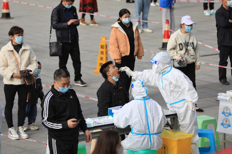 A medical worker in a protective suit collects a swab from a man during a mass nucleic acid testing in Huichuan district following new cases of Covid-19 in Zunyi, Guizhou province, China, on October 23.