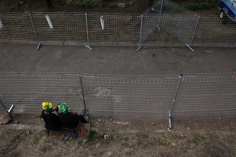 Two woman wait for the arrival of Winnie Madikizela-Mandela's coffin in Soweto on April 13 2018.