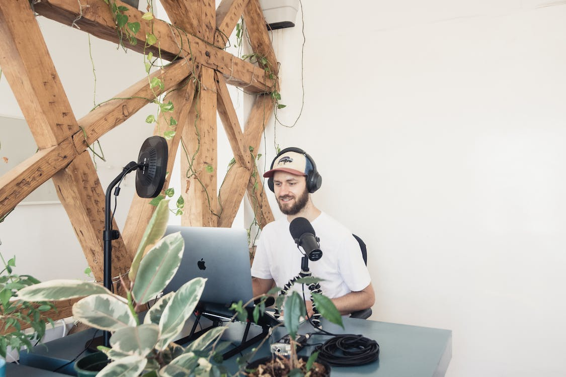 A Man in White Crew Neck T-shirt Doing a Podcast with headphones on