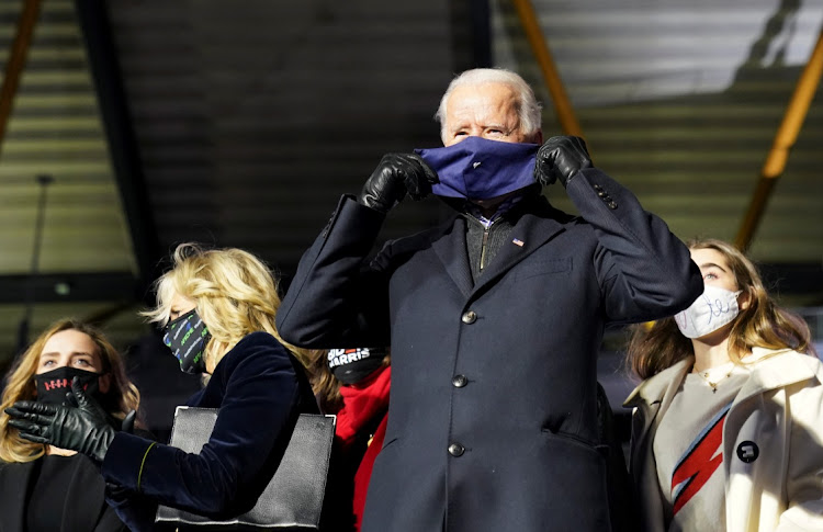 Democratic U.S. presidential nominee and former Vice President Joe Biden puts on a face mask while standing onstage with his family during a drive-in campaign rally in Pittsburgh, Pennsylvania, U.S., November 2, 2020.