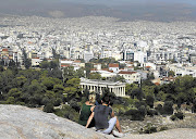 Tourists on a hill in Athens view the archaeological site of the Acropolis in Greece. File photo.