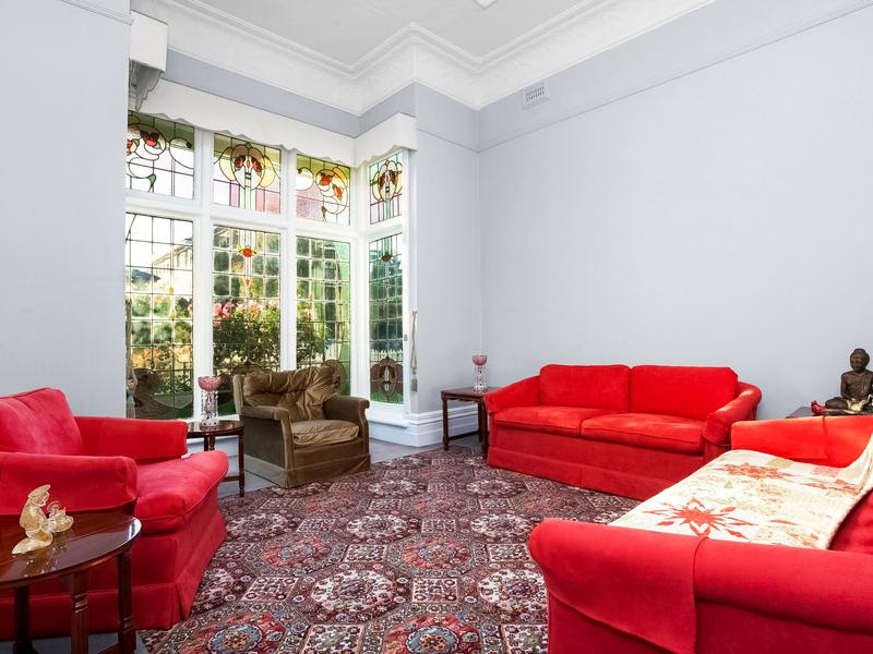 Lounge room with marvellous bay window at 74 McPherson Street, Essendon VIC 3040. Note the ornate ceilings and cornice work, typical of the period.