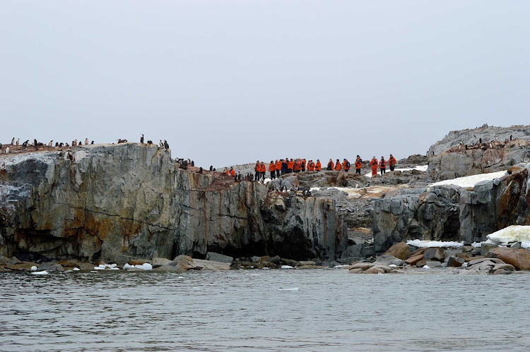 Members of a Lindblad expedition atop a rock outcropping on Antarctica.
