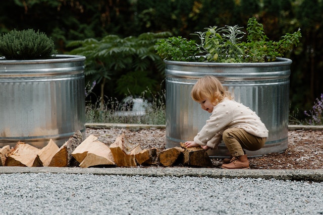 child playing outdoors with wood