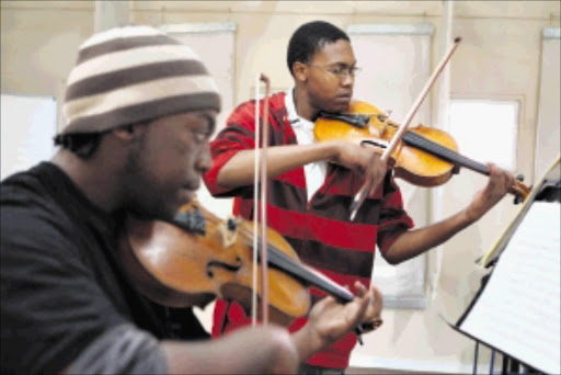 IN HARMONY Tiisetso Mashishi and Kabelo Monnathebe are student teachers at Buskaid. Pic.James Oatway. 13/08/2009. © St. Tiisetso Mashishi (21) and Kabelo Monnathebe (19) (foreground) practice. The young men have been awarded a scholarship to study at the Royal Academy of Music in London. They are student/teachers at Buskaid, a music academy in Soweto founded by Rosemary Nalden. Picture: JAMES OATWAY 2009/08/13.