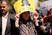 People attend a protest against American airstrikes in Syria, in front of the United Nations (UN) building in Damascus, Syria April 8, 2017. The yellow placard reads in Arabic 