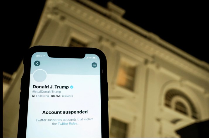 A photo illustration shows the suspended Twitter account of U.S. President Donald Trump on a smartphone and a lit window in the White House residence in Washington, U.S., January 8, 2021