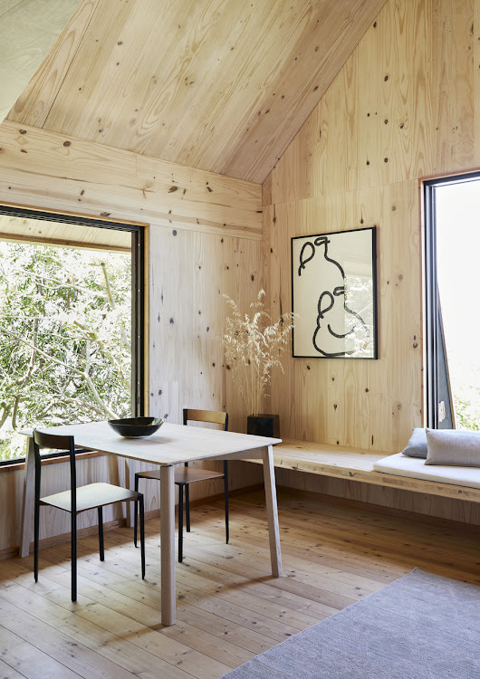 Set next to generous windows, the dining area is positioned unobtrusively between the kitchen and living areas. The dining table, a basis table in ash wood by Hoop Furniture, is positioned in conversation with the Cape Ash tree in the garden. The MŪ191 chairs are by MŪVEK, a furniture design studio based in Cape Town. The artwork is by Dale Lawrence.