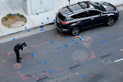 A police evidence technician photographs the crime scene after an early-morning shooting in a stretch of downtown near the Golden 1 Center arena in Sacramento, California, US April 3, 2022. 